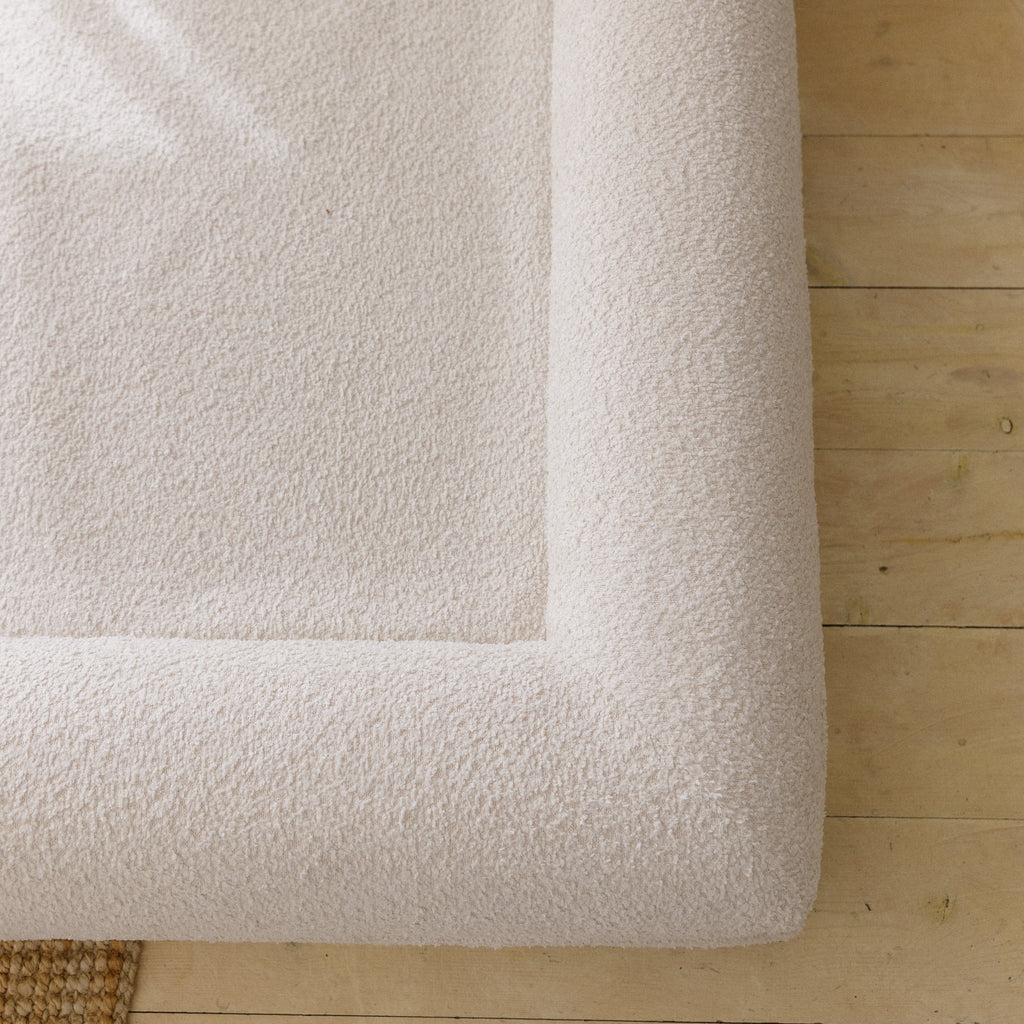 Close-up of the soft, textured 690GSM cream boucle fabric cover on the dog bed