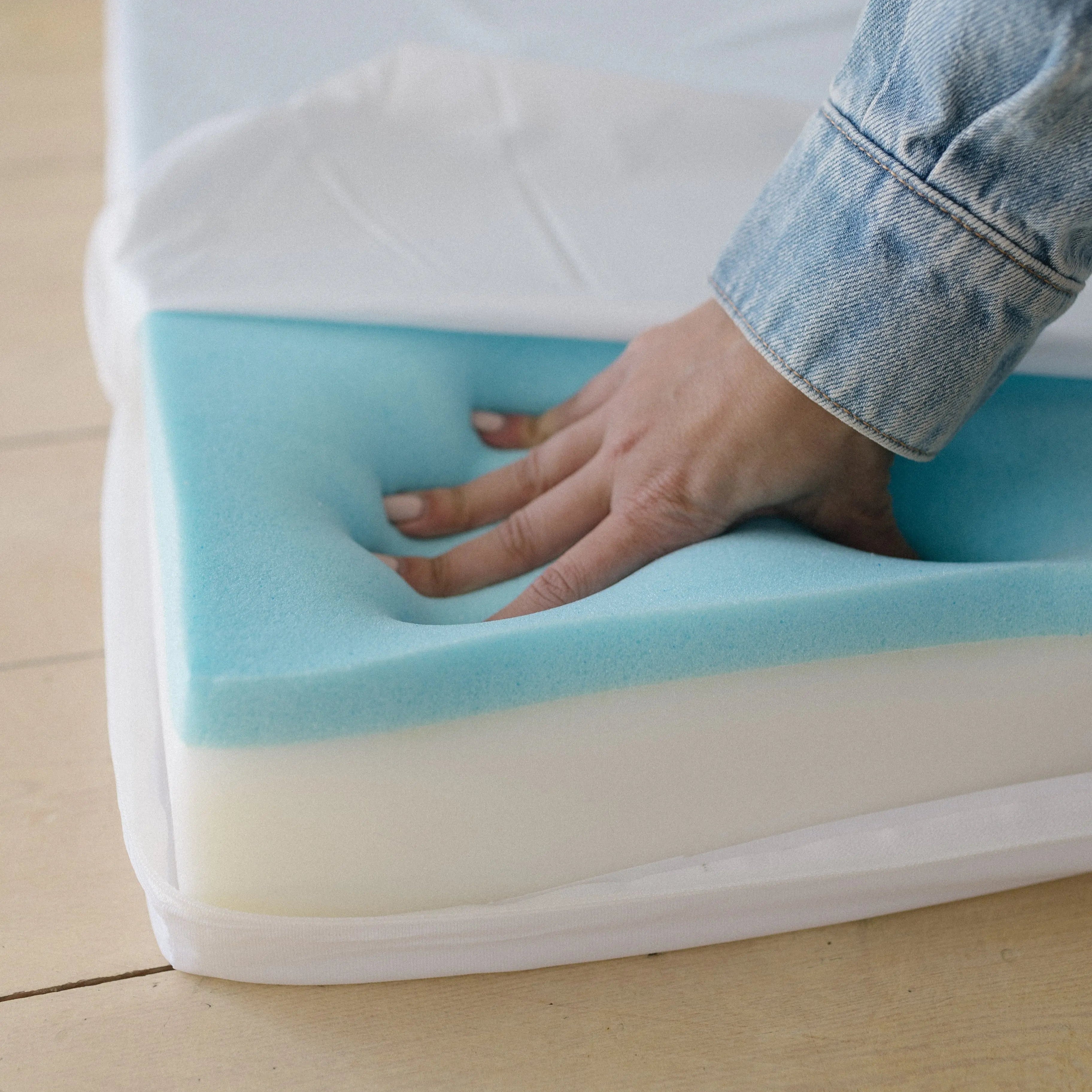 Hand pressing down on the memory foam base, showing the density of the foam