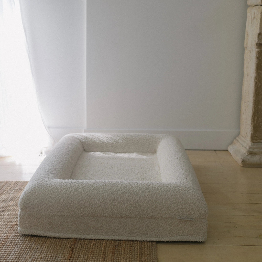 Image of Small/Medium Bouclé Dog Bed with cream boucle fabric and memory foam, styled on a wooden floor