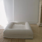 Image of Small/Medium Bouclé Dog Bed with cream boucle fabric and memory foam, styled on a wooden floor