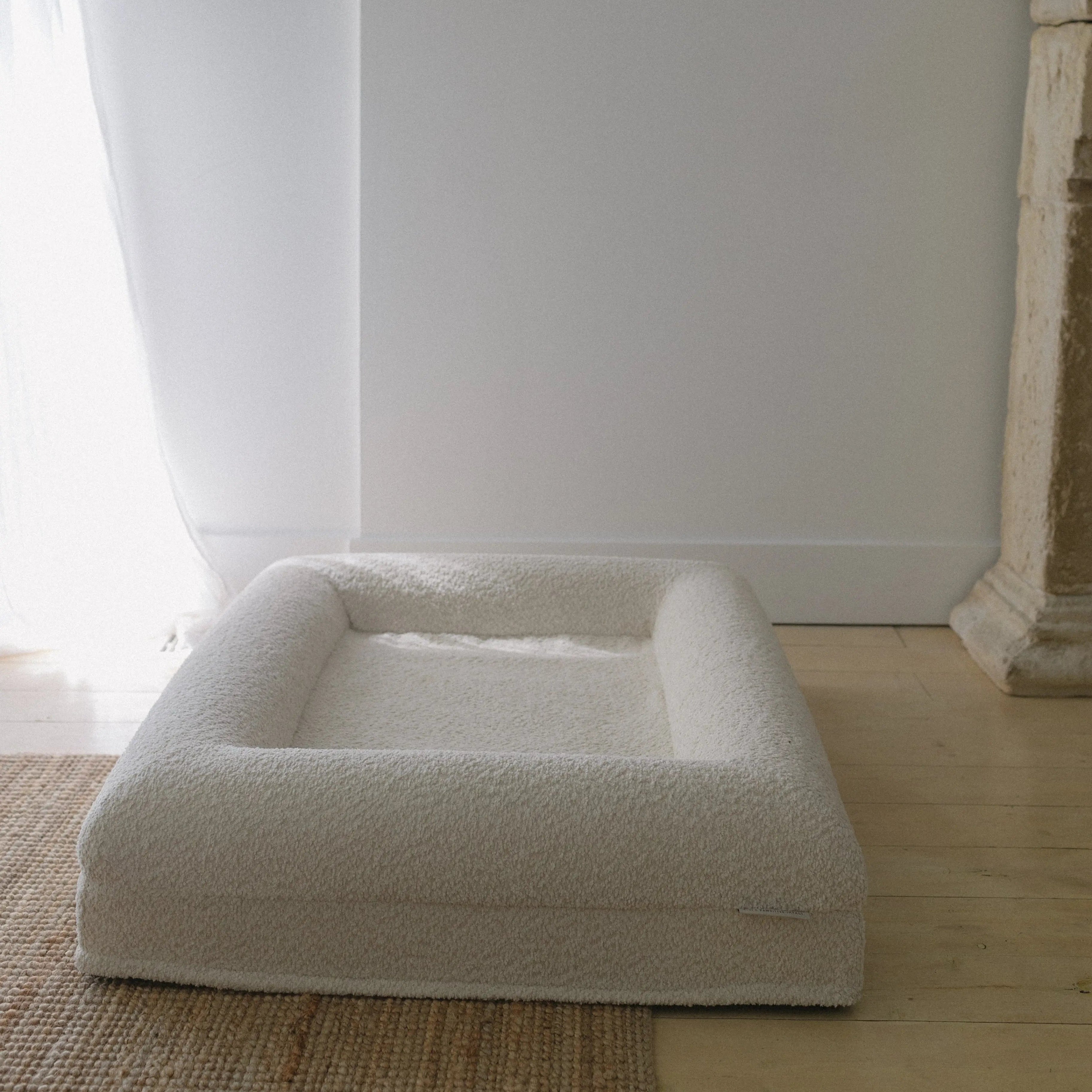 Image of Small/Medium Bouclé Dog Bed with cream boucle fabric and memory foam, styled on a wooden floor